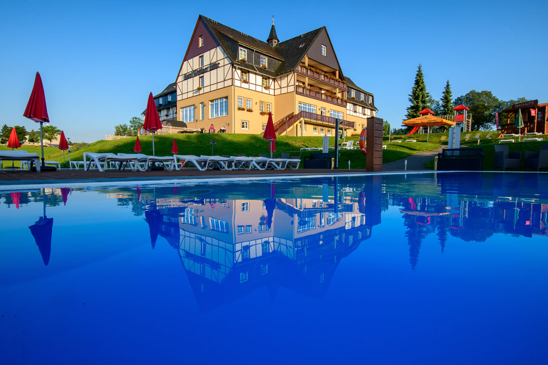 Ein Pool mit einem Gebäude und Stühlen.